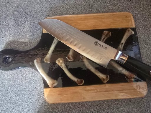 Chef's knife on a wooden cutting board with bone shapes.